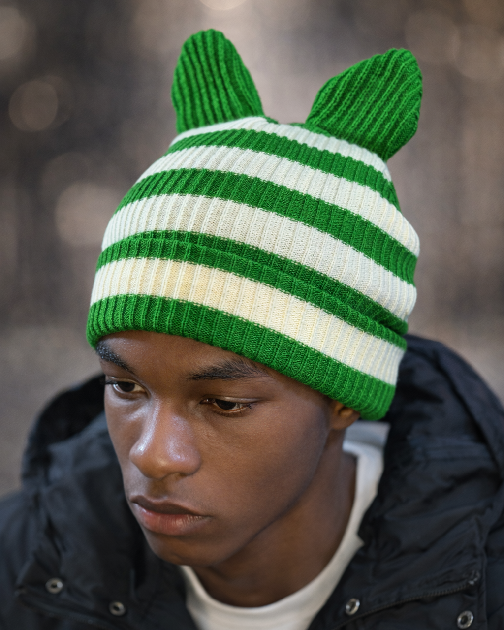 Person wearing a green and white striped knit hat with animal ears against a blurred background